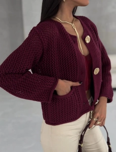 Détail d'un cardigan bordeaux au crochet avec boutons dorés et maille ajourée raffinée