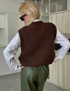 Rear view of a dark brown chunky knit vest featuring vertical ribbed textures and sleeveless cut