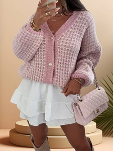 Gros plan détaillé d'un gilet en maille torsadée rose avec texture de fils blancs et boutons