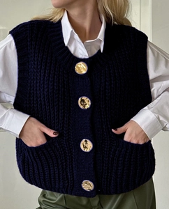 Detail of navy knit vest with textured gold buttons over white shirt