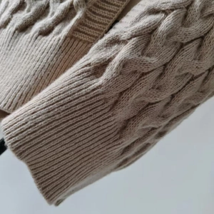 Close-up of oatmeal cable knit sleeves and ribbed cuffs on an autumn cardigan