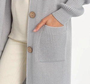 Macro detail of gray knitted cardigan featuring thick weave texture and large patch pocket