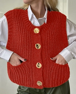 Detail of red cable knit vest featuring round neck and gold textured buttons decoration