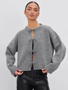 Detail view of the gray knitted cardigan featuring four delicate front bow tie closures