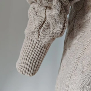 Detail of cable-knit texture and ribbed cuffs on a beige oversized cardigan sweater
