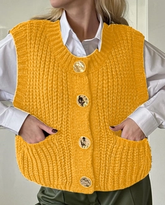 Close-up of a yellow knitted vest featuring golden metal buttons and practical front pockets