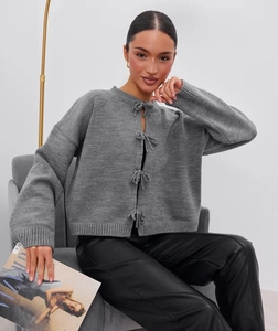 Close-up of grey knit cardigan featuring elegant four-bow ribbon front closure detail