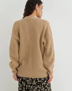 Back view of a chunky beige knit cardigan featuring loose ribbing and drop shoulders