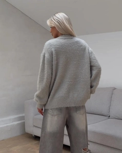 Dettaglio del cardigan in maglia grigia con polsini a coste e vestibilità rilassata