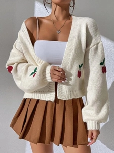 Detail of chunky knit cream cardigan with cherry embroidery and textured cable pattern