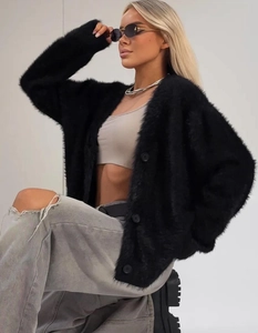 Dettaglio del cardigan nero in finta pelliccia con texture soffice e grandi bottoni