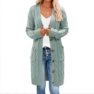 Dettaglio del cardigan lungo in maglia a trecce verde salvia con bottoni marroni e tasche