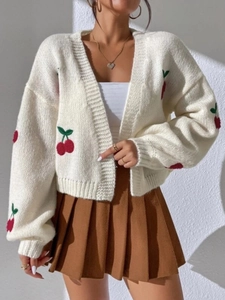 Detail of red cherry embroidery on a cream white knit cardigan with rib cuffs