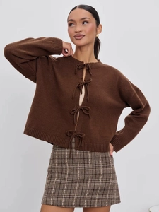 Detail of dark brown knitted cardigan featuring decorative bow closures and ribbed cuffs