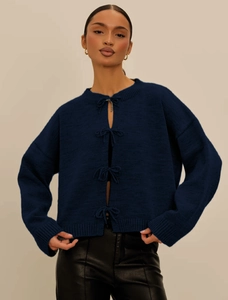 Detail of dark blue knit cardigan featuring four front ribbon bow-tie closures