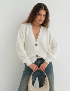 Close-up of white rib-knit cardigan with deep V-neck and dark brown wooden buttons