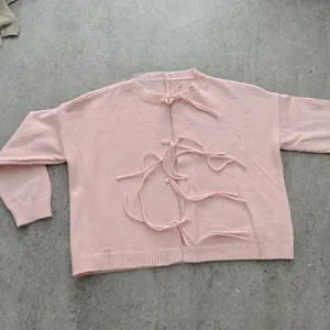 Detail of light pink knitted cardigan featuring unique front tie-up closure and ribbed cuffs