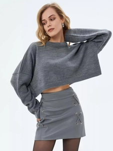 Detail of grey cropped knit sweater paired with a lace-up skirt and metal hardware