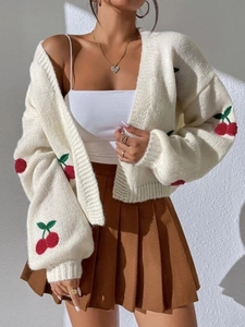 Close-up of cherry embroidery on soft cream knit cardigan with relaxed shoulder design