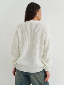 Back view of a white chunky knit sweater for women styled with casual blue denim jeans