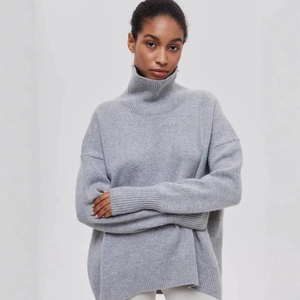 Détail d'un pull gris à col roulé oversize avec poignets côtelés et texture en maille