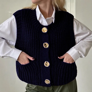 Women's navy sleeveless knit vest with round neck and gold buttons over white shirt