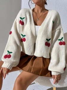 Detail of white chunky knit cardigan featuring red cherry embroidery and ribbed cuffs