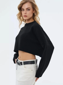 Detail of a cropped black knit sweater with drop shoulder and ribbed crew neck finish