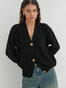 Detail of black knit cardigan featuring large wooden buttons and chunky textured fabric