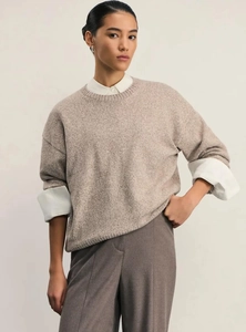 Detail of light brown knit sweater layered with white collared shirt and gray trousers