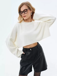 Detail of a white cropped knit sweater with crew neck and long drop-shoulder sleeves