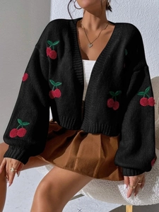 Detailed close-up of cherry embroidery and cable knit texture on a black cardigan