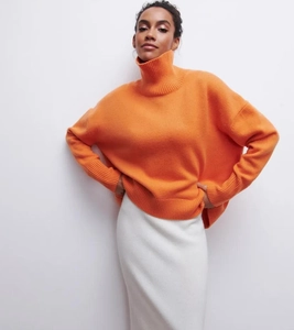 Détail d'un pull orange à col montant avec poignets côtelés et épaules tombantes