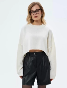 Detail of white knit sweater showing ribbed crew neck and soft oversized texture