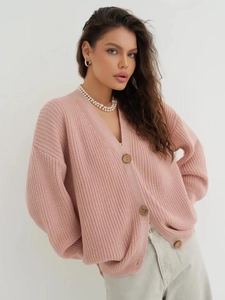 Detailed close-up of pink oversized knit cardigan with classic wooden buttons and soft texture