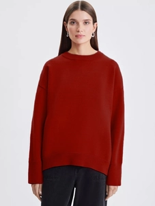 Detailed close-up of brick red knit sweater showing ribbed cuffs and thick wool texture