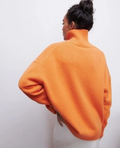 Vue détaillée du pull orange à col roulé oversize avec poignets côtelés et épaules tombantes