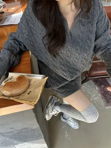 Detail of grey cable-knit polo sweater in a cozy lifestyle setting with a relaxed fit