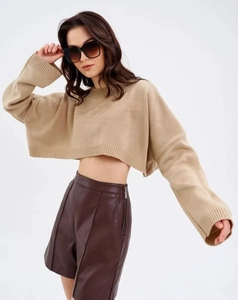 Detailed texture of beige cropped knit sweater with ribbed cuffs and drop shoulder style