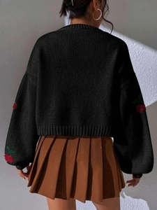 Detail of red cherry embroidery on black knit cardigan sleeve for a vintage look