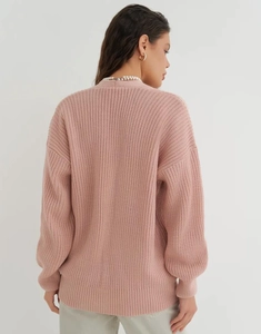 Macro detail of the pink knitted cardigan showing thick ribbed texture and drop shoulder