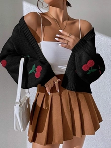 Close-up of cherry embroidery details on black knitted cardigan sleeve with ribbed cuffs