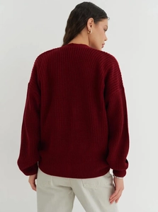 Detail of burgundy thick knit sweater showing textured vertical patterns and ribbed cuffs