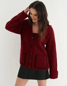 Detail of burgundy V-neck cardigan featuring thick knit texture and black contrast pockets