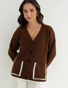 Detail of dark brown knit cardigan featuring white contrast trim on pockets and V-neckline