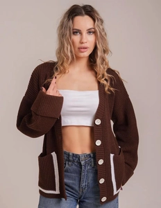 Close-up of chunky knit cardigan with contrast pocket trim and large white buttons