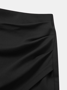 Détail des coutures froncées et du tissu élastique sur une mini-jupe noire taille haute