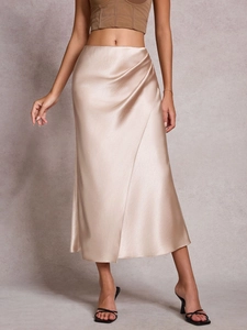 Close-up of elegant champagne satin midi skirt with side gathering and draped waist detail
