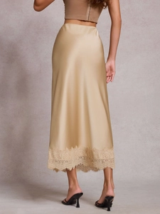 Détail d'une jupe midi en satin champagne avec bordure en dentelle délicate et soyeuse