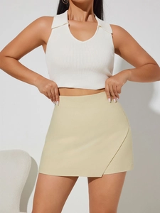 Detail of white ribbed knit halter top paired with pale yellow asymmetrical mini skirt